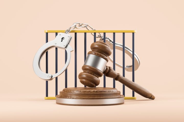 Closed handcuffs hanging on jail bars and gavel