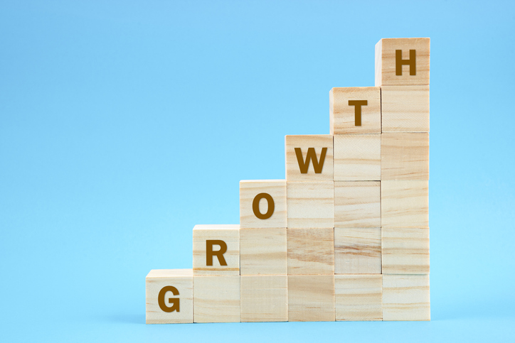 Growth word on wooden blocks staircase on blue background.