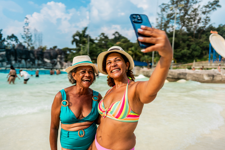 Mother and daughter taking selfie or filming at water park