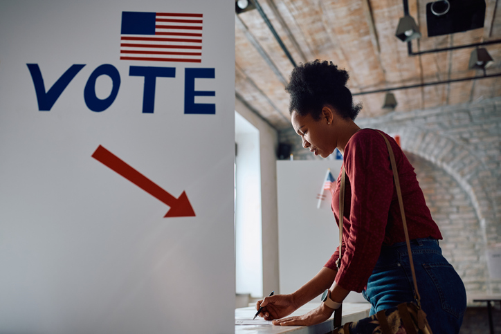 African American female citizen voting at polling place during US elections.