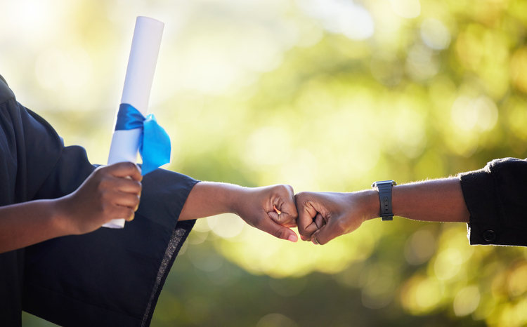 Graduation, education and hands of friends fist bump in celebration of certificate, study and success on bokeh. University, people and hand in support of goal, motivation and unity in accomplishment