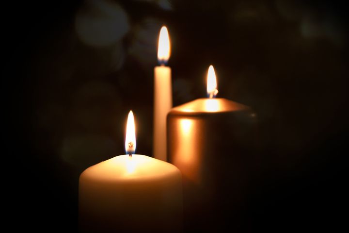 Funeral symbol with burning candle in darkness