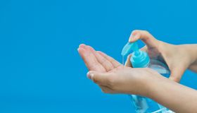 Woman clean hands with hand sanitizer on blue background