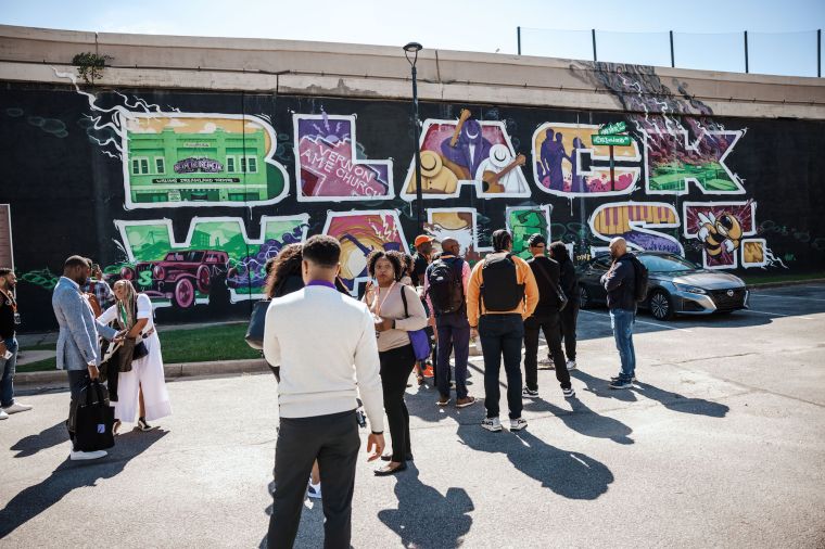 A walking tour happening alongside a Black Wall Street mural