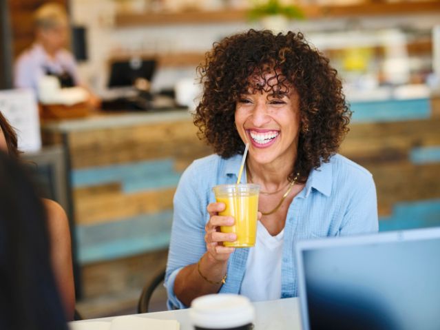 Happy Woman With a Smoothie in a Small Cafe