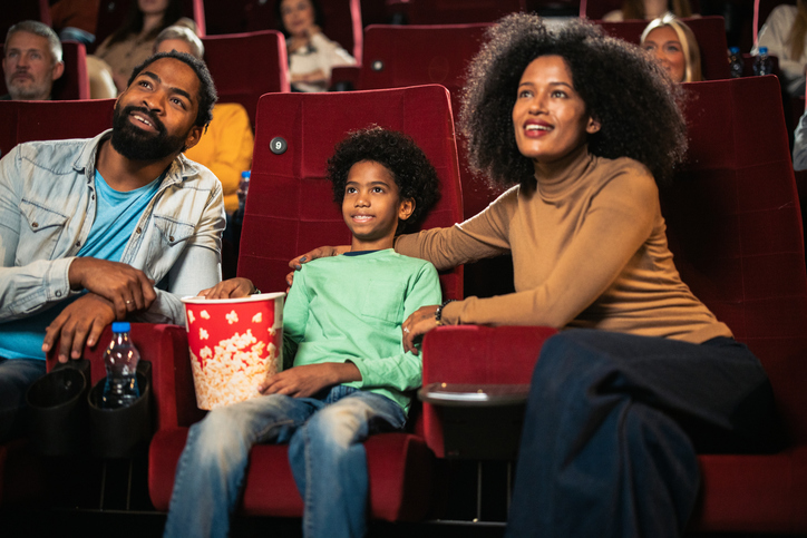 Happy couple and their boy enjoying a family movie at the cinema