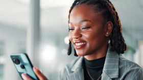 Black woman, phone and smile for social media post, communication or meme online on work break. Relax, happy and female employee on mobile app for chat, notification or reading digital ebook or email