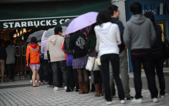 Customers line up outside a Starbucks co