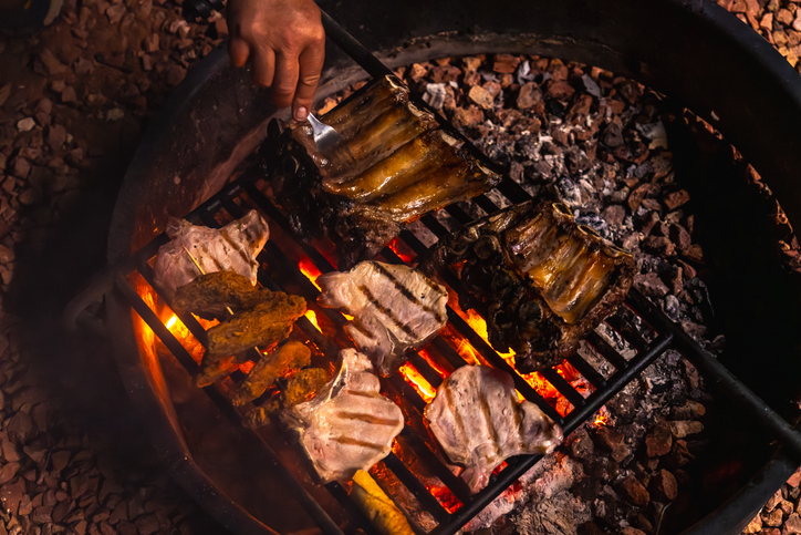 Cooking barbecue ribs and steaks on campfire grill
