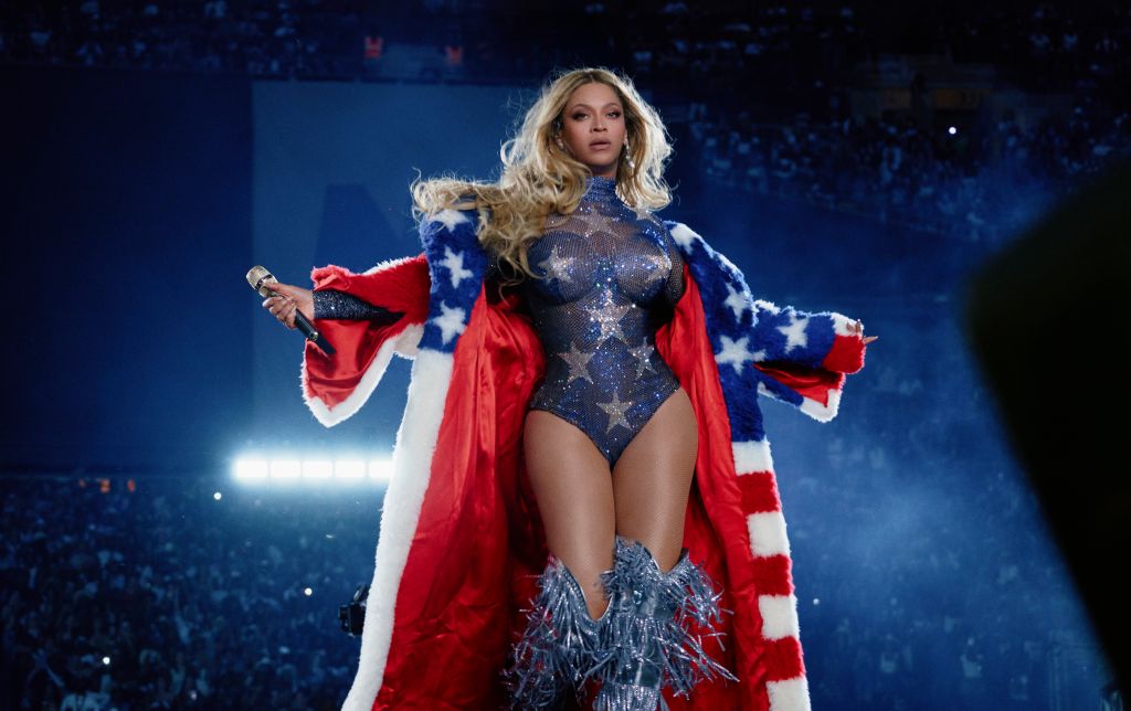 A woman wearing a red, white, and blue costume with stars and stripes, performing on a stage with a blue background and lights.