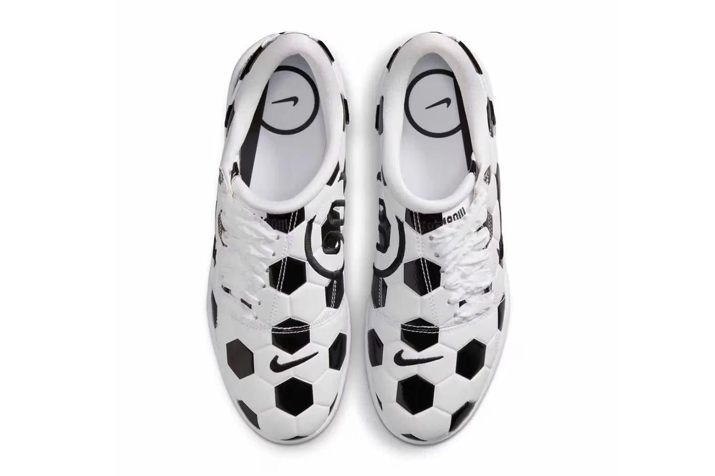 A pair of white and black Nike soccer cleats with a hexagonal pattern design.