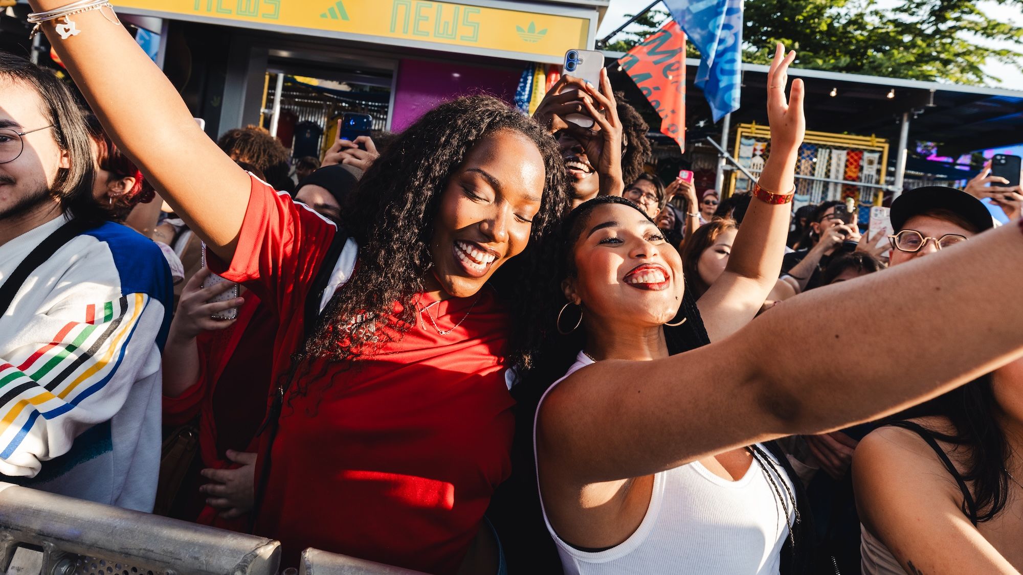 A crowd of people, many with their arms raised, celebrating and smiling at an event or festival.