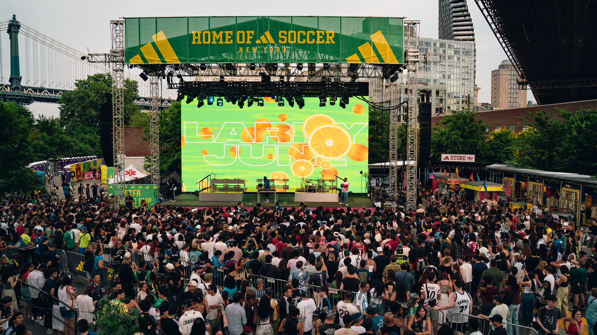 Crowded outdoor concert venue with large "Home of Soccer" banner and colorful stage backdrop featuring the text "Lollapalooza".