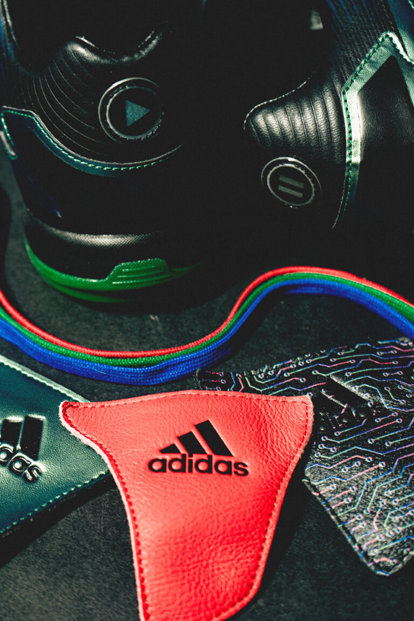 Close-up of a black and green sports helmet with the Adidas logo on a red leather strap.