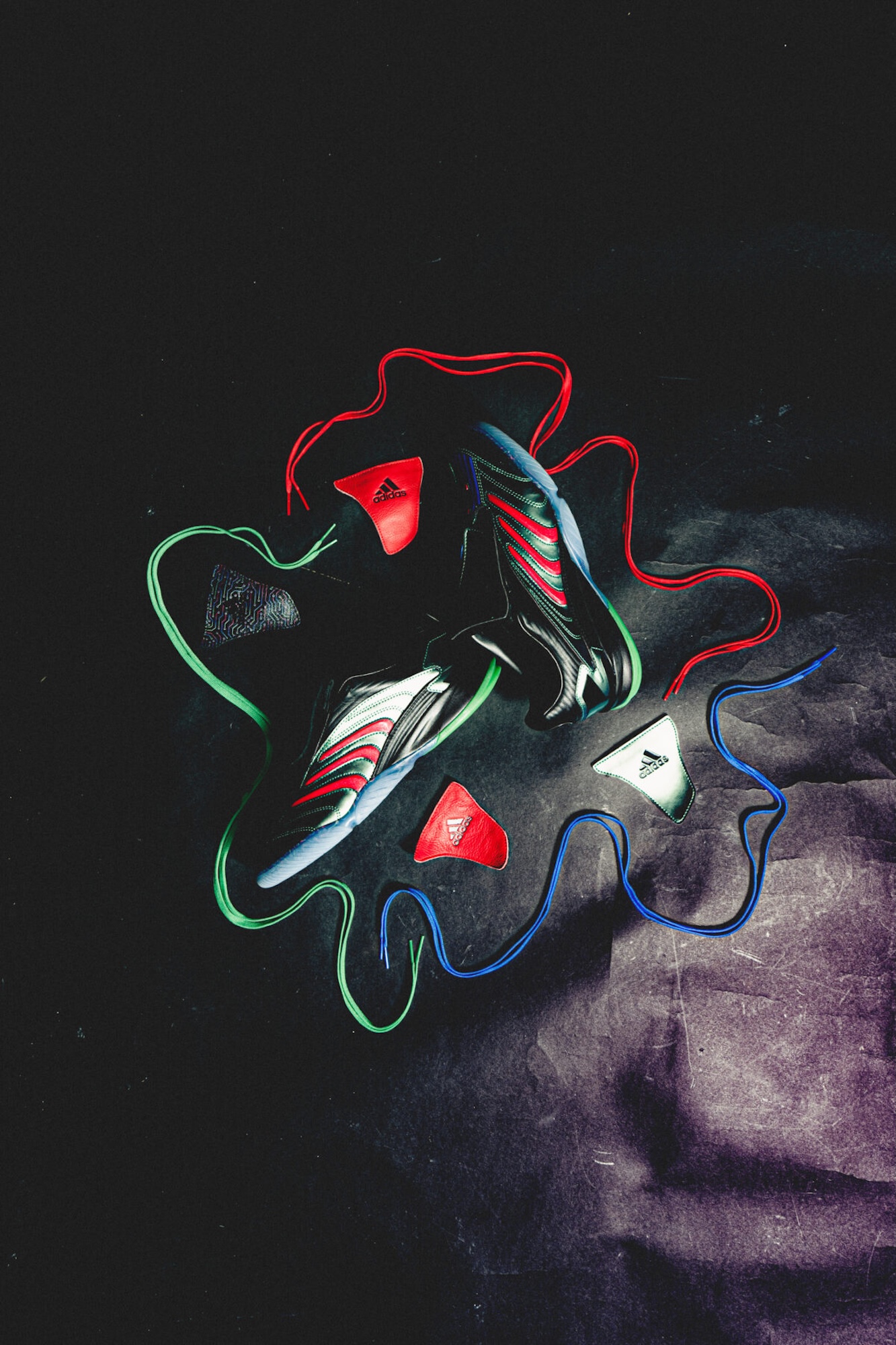 Colorful Adidas sneakers and accessories arranged on a dark background.