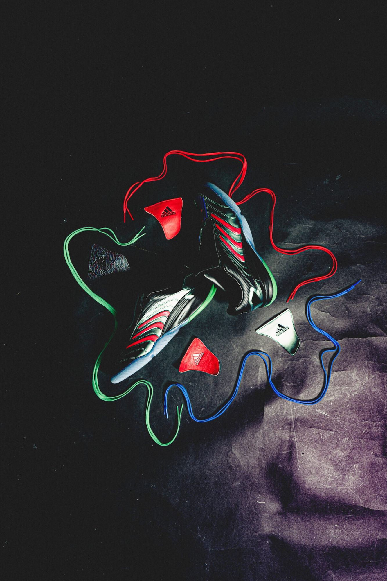 Colorful Adidas sneakers and accessories arranged on a dark background.