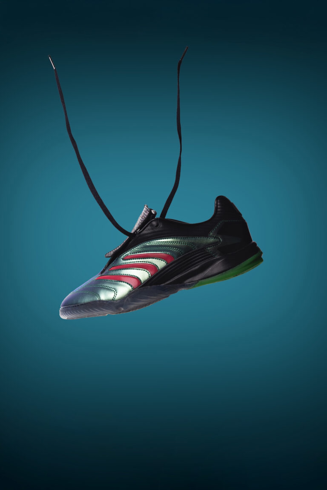 A black and green athletic shoe with red and white accents, floating against a teal background.