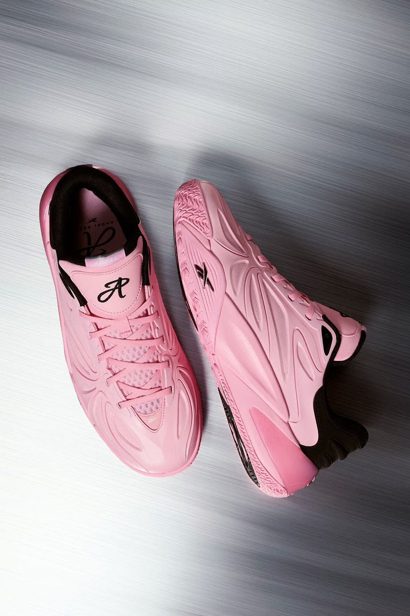 Pair of pink athletic shoes with textured soles and "Reebok" branding, blurred against a gray background.