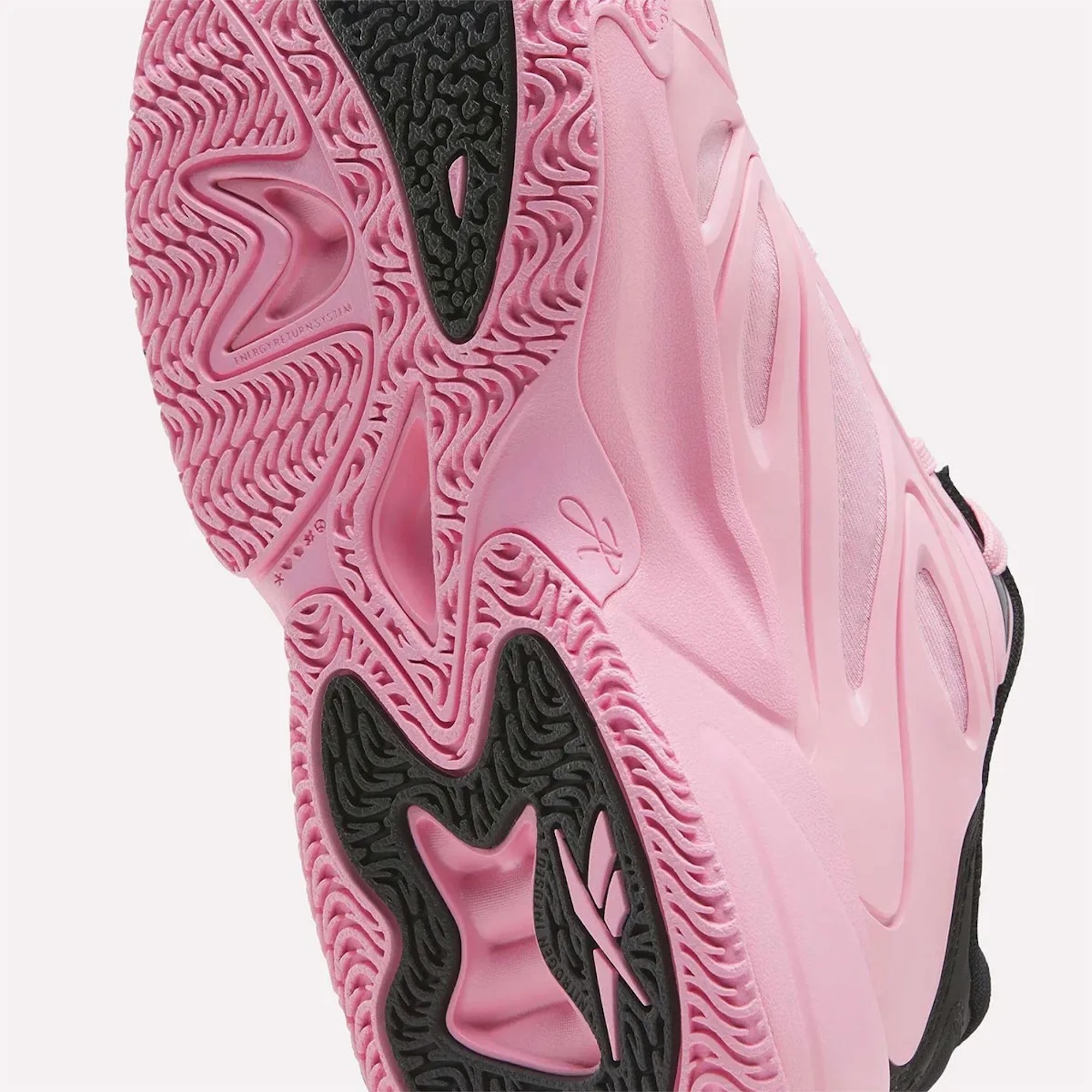 Close-up of a pink and black athletic shoe with intricate textured patterns on the sole and upper.