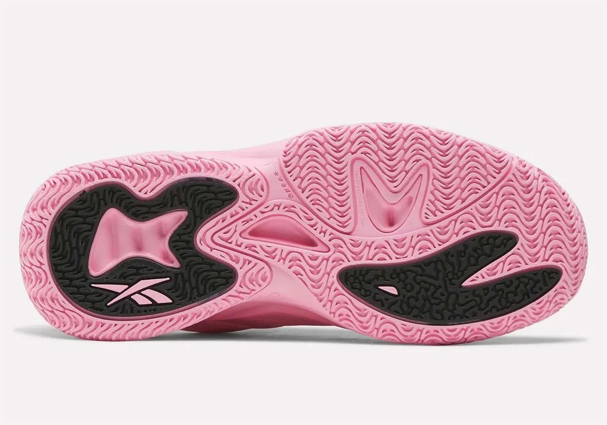 A pink and black sneaker with a distinctive sole pattern and Reebok branding.