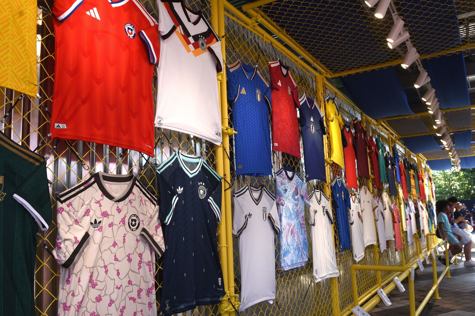 A display of various sports jerseys and uniforms, including national team jerseys in red, white, and blue colors.