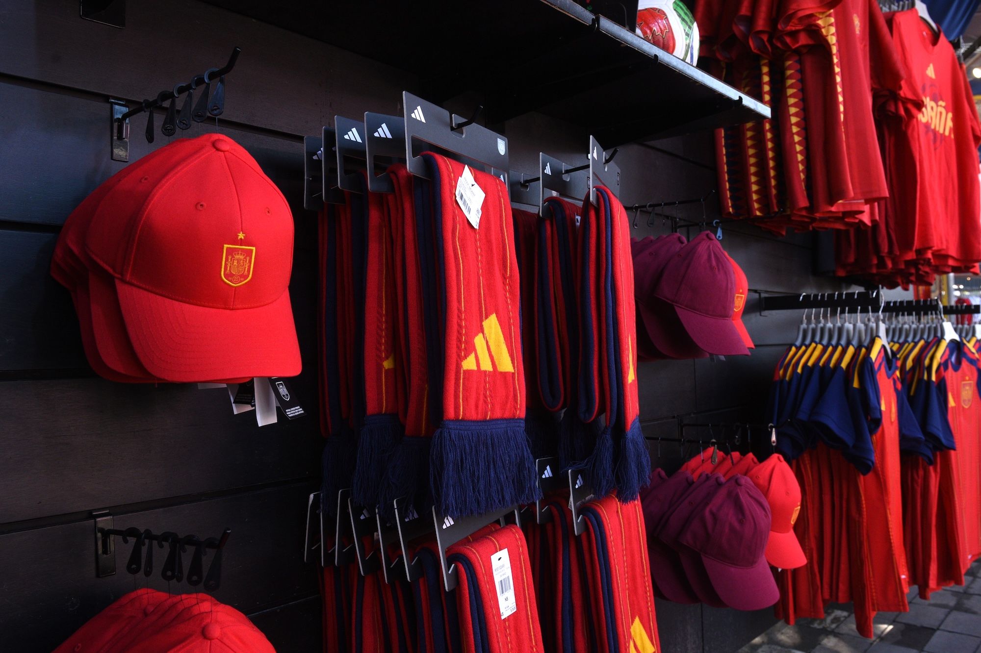Shelves displaying various red and yellow soccer jerseys, shorts, and caps with the Adidas logo.