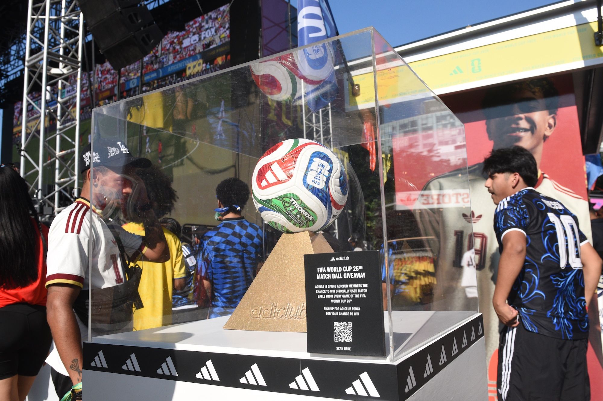 A display showcasing a FIFA World Cup 2022 match ball, surrounded by Adidas branding and imagery of soccer players.