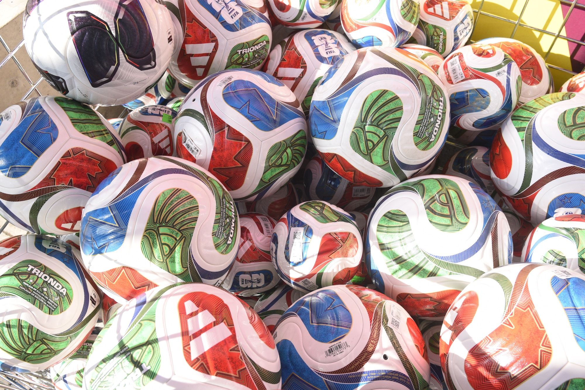 Pile of colorful soccer balls with various team logos and designs.