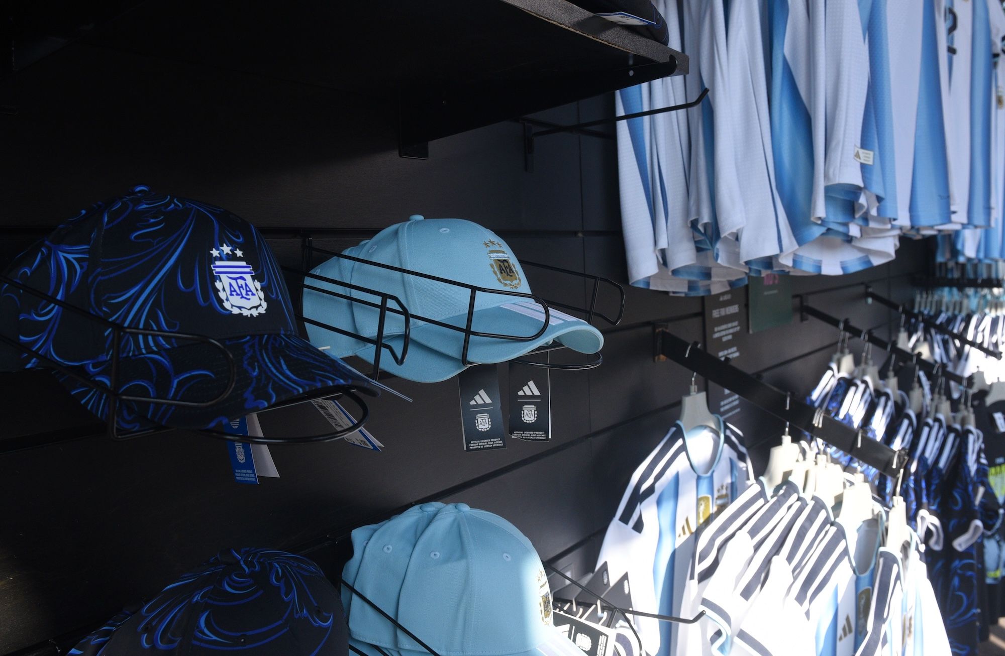 Shelves displaying Argentina national team jerseys, hats, and other merchandise in a sports store.