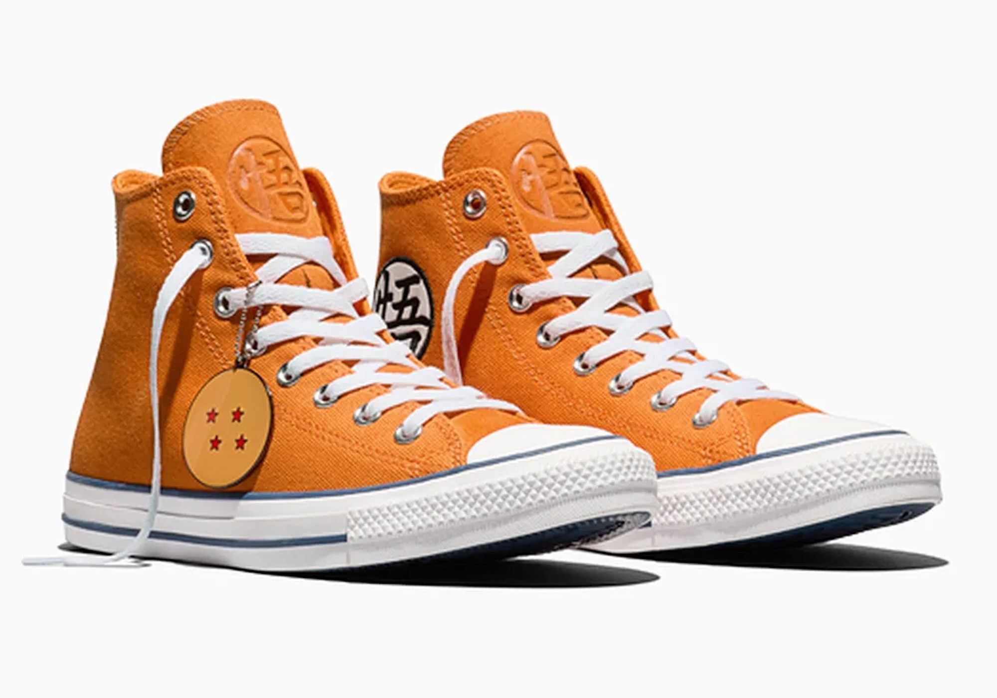 A pair of orange high-top sneakers with white laces and a Dragon Ball Z logo charm.