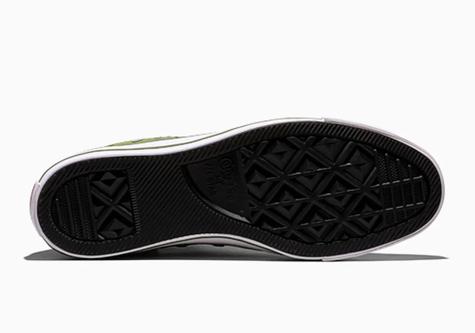 Black and white sneaker with green accents and a textured sole.