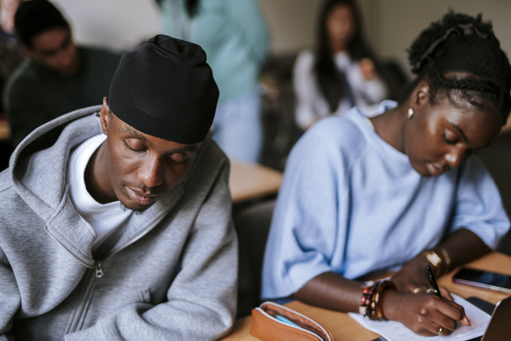 Focused young male student wearing do rag studying in university at classroom