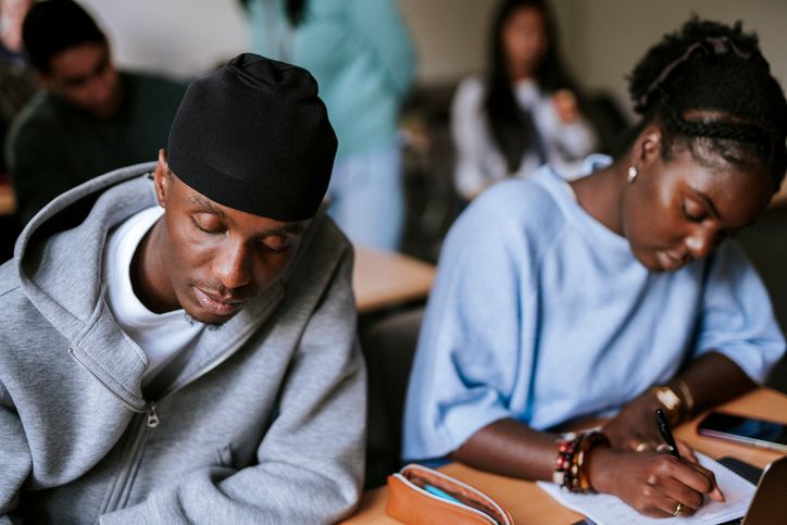 Focused young male student wearing do rag studying in university at classroom