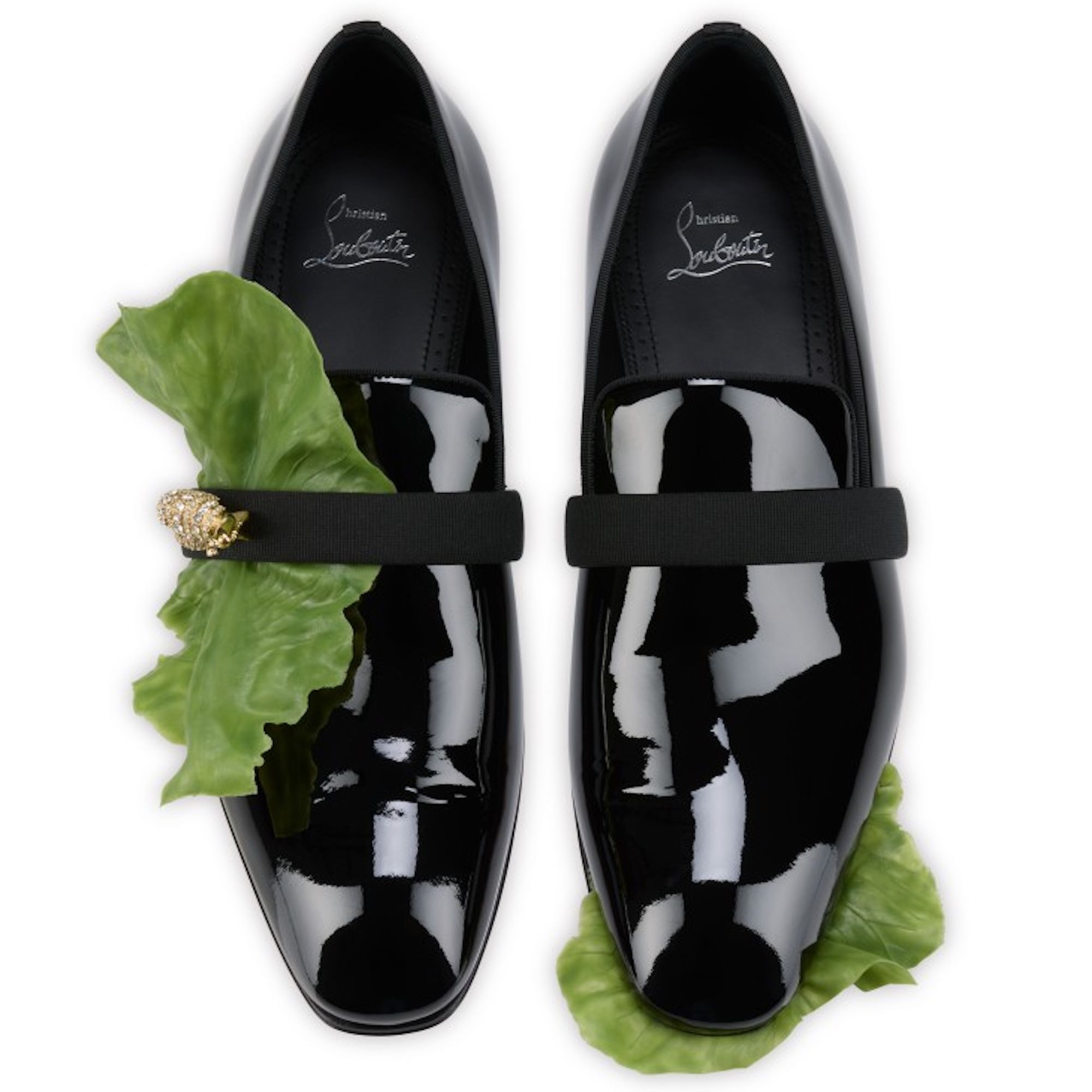 Black patent leather dress shoes with a green leaf accent and gold-colored ornament.