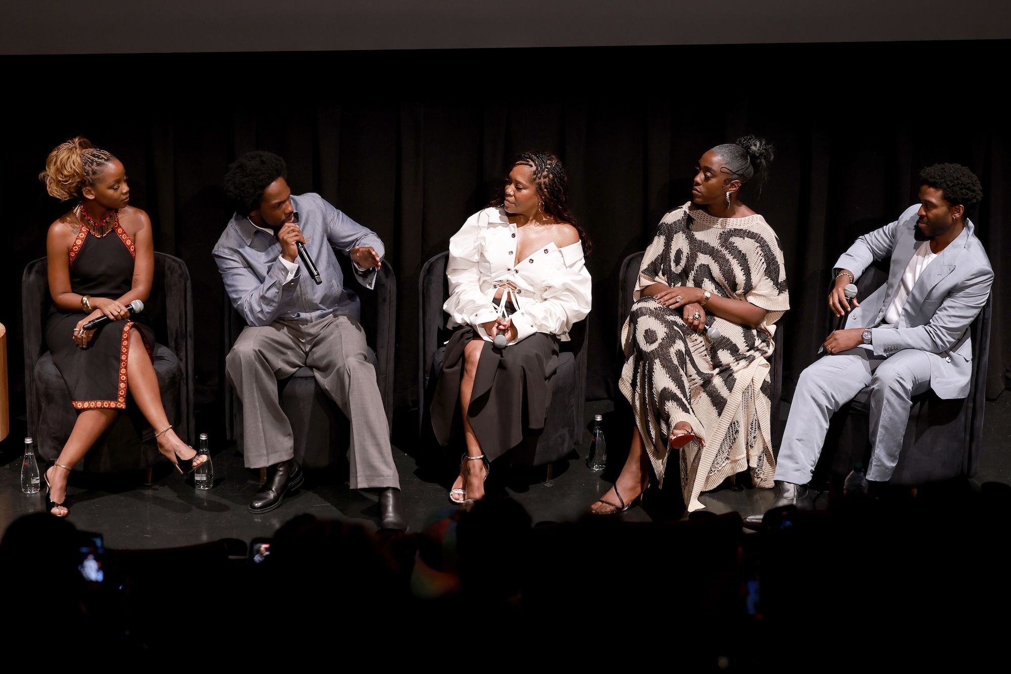 Five people, including Thuso Mbedu, Tosin Cole, Regina King, Lashana Lynch, and Zackary Momoh, seated on a stage speaking at a film event.