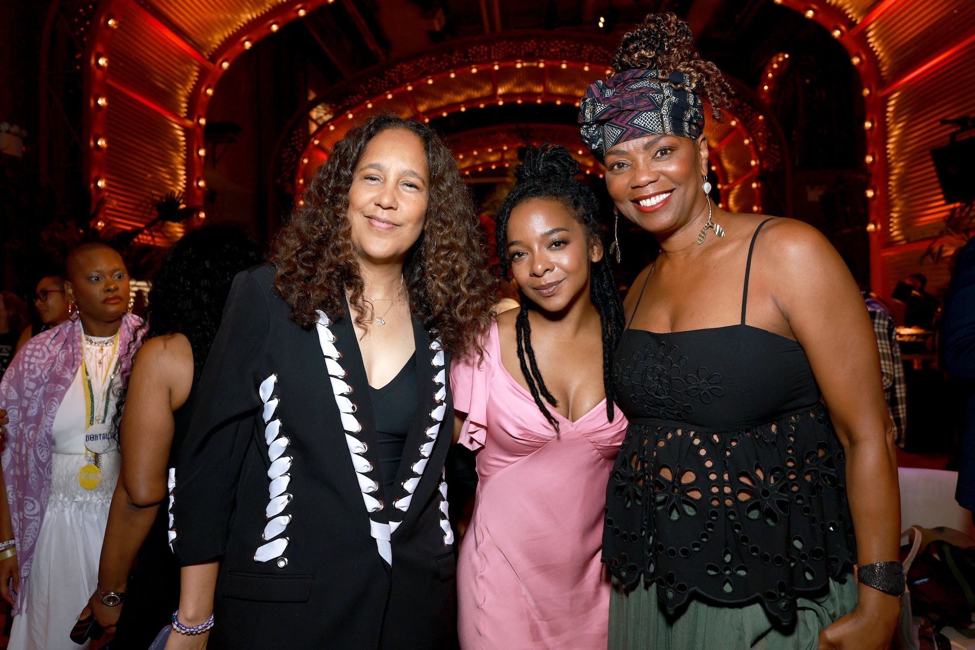 Three women posing together at an event, smiling and dressed in stylish outfits.