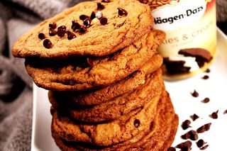 A stack of freshly baked chocolate chip cookies on a plate, with chocolate chips visible on the surface.