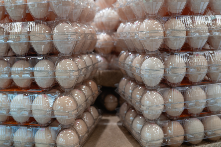 Eggs in transparent plastic cartons on supermarket shelves.
